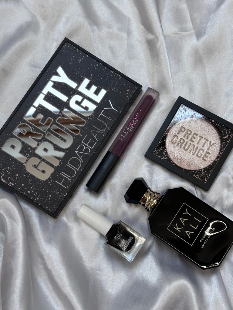 Huda Beauty-make-up en Kayali Vanilla Oud-parfum op witte satijnstof